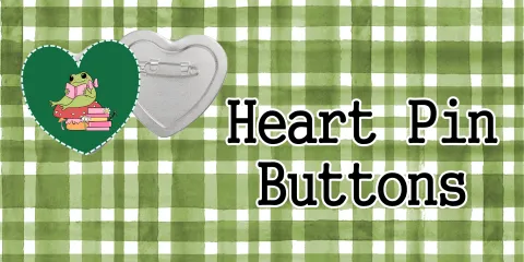 heart-shaped pin button with a green frog decal on a green plaid background