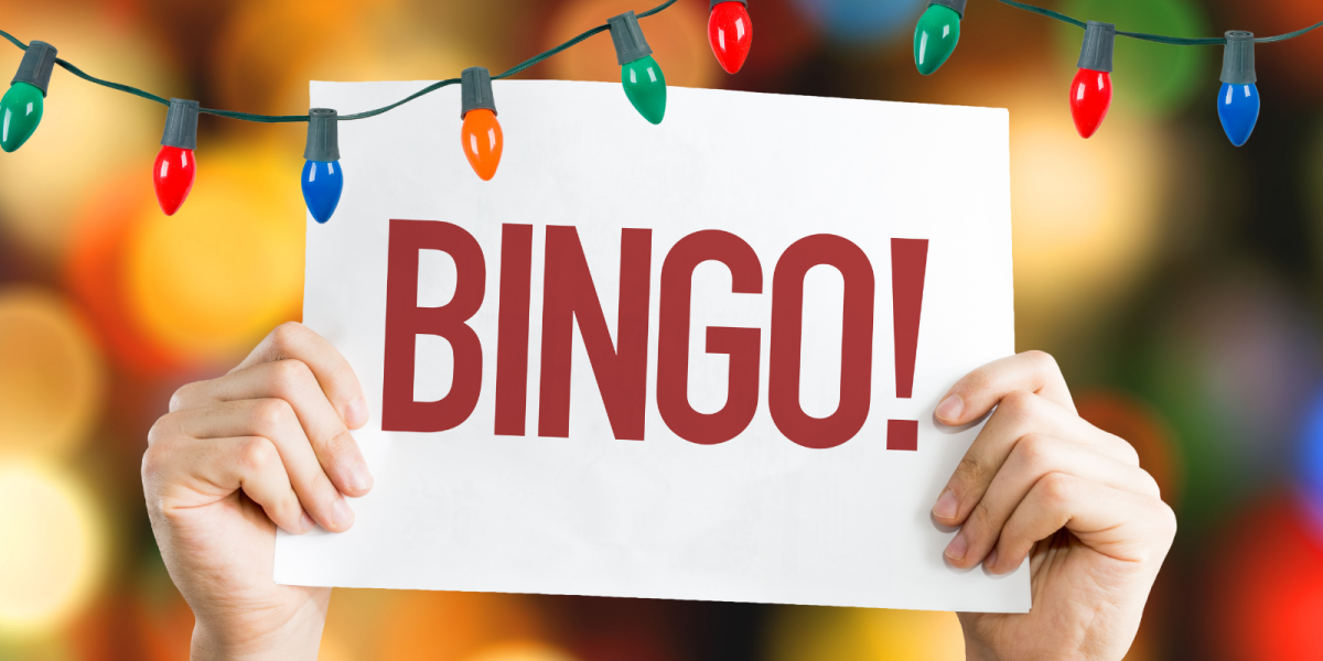 Two hands hold a giant sign that reads "Bingo!" There are two strings of red and green lights. 